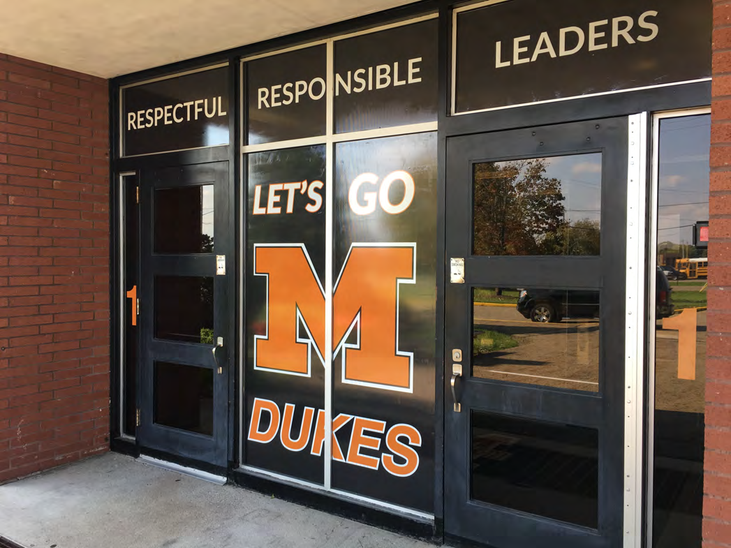 School entry graphics with orange Dukes lettering and school values above the doors