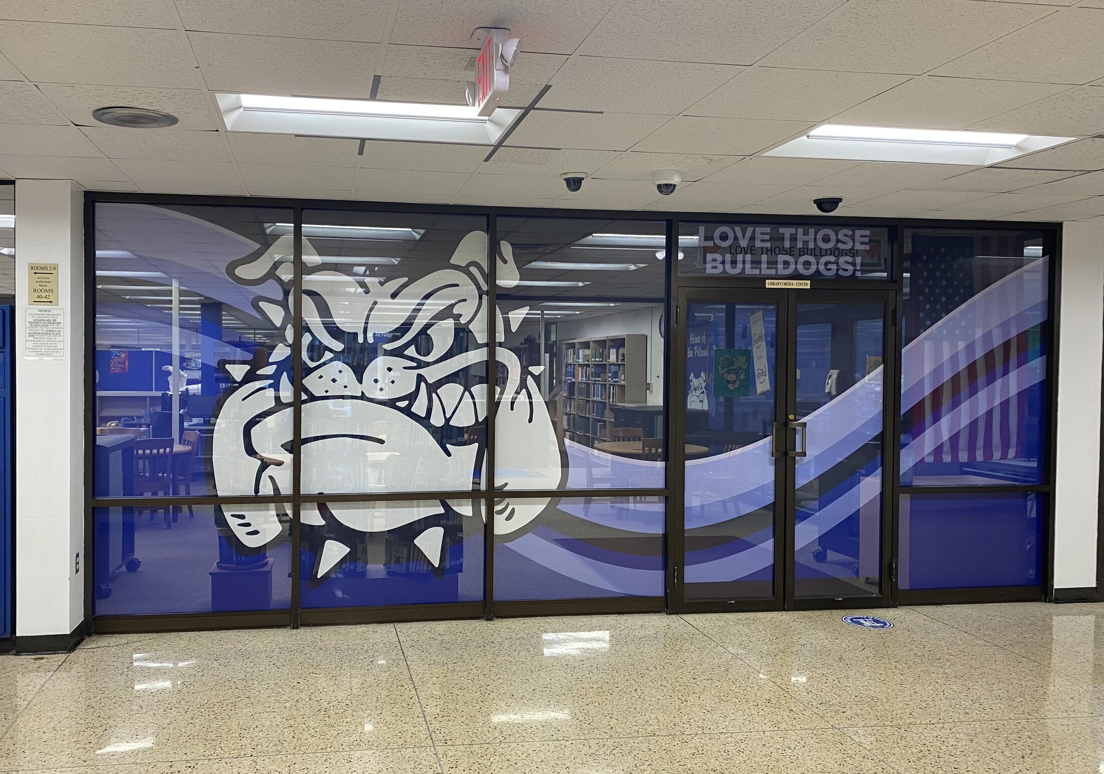 Blue and white bulldog mascot graphics across a school library and media-center glass wall