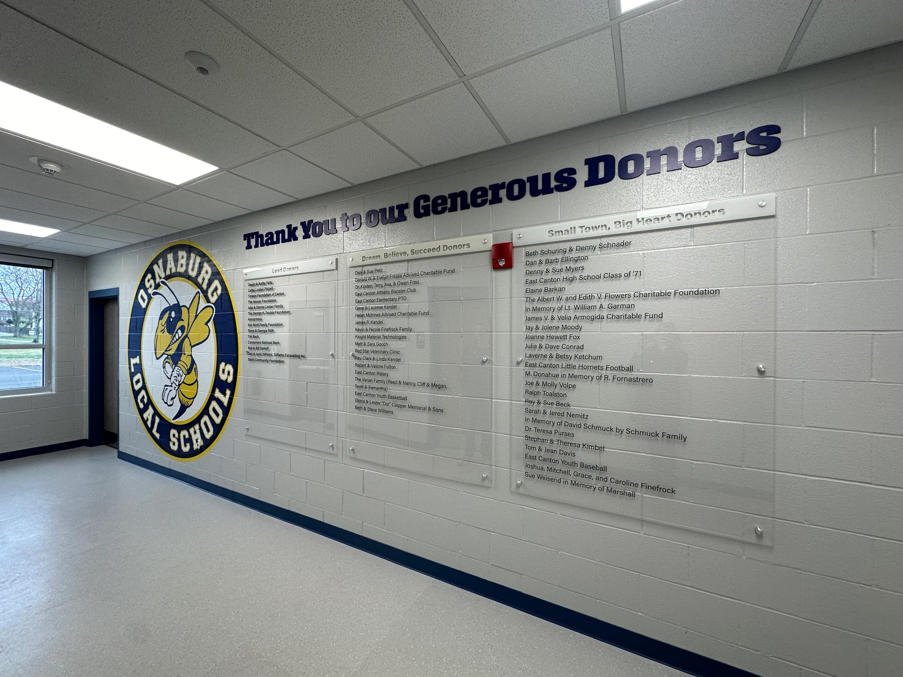 Osnaburg Local Schools donor recognition wall with a Hornets mascot, dimensional lettering, and clear standoff donor panels